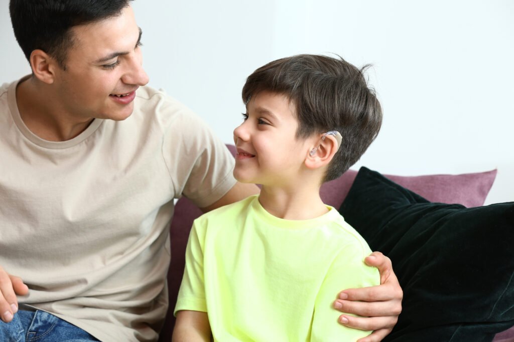 Young man and his son with hearing aid